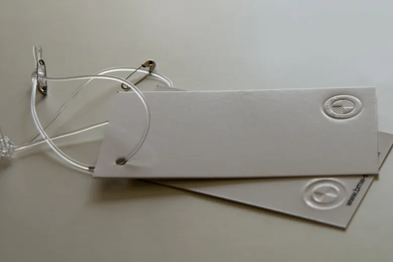 Etiquetas de cartão cinzento com relevo seco e cordão transparente