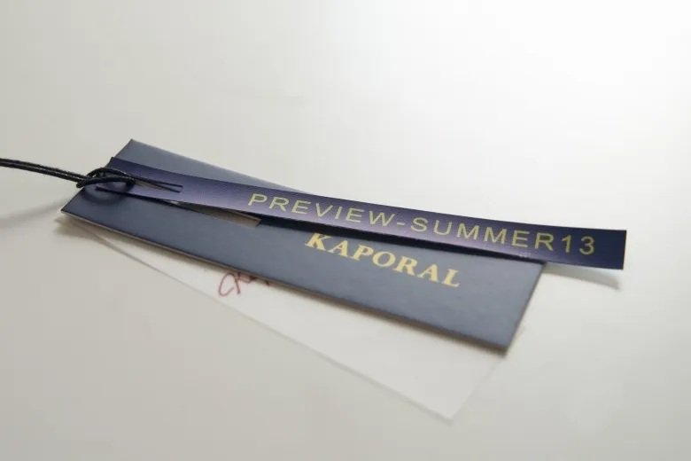 Etiquetas sobrepostas com texto em metalizado dourado e cordão preto